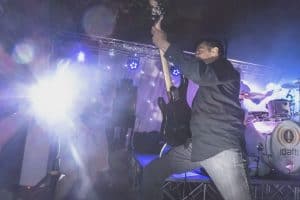 Marc holding guitar up with bright lights